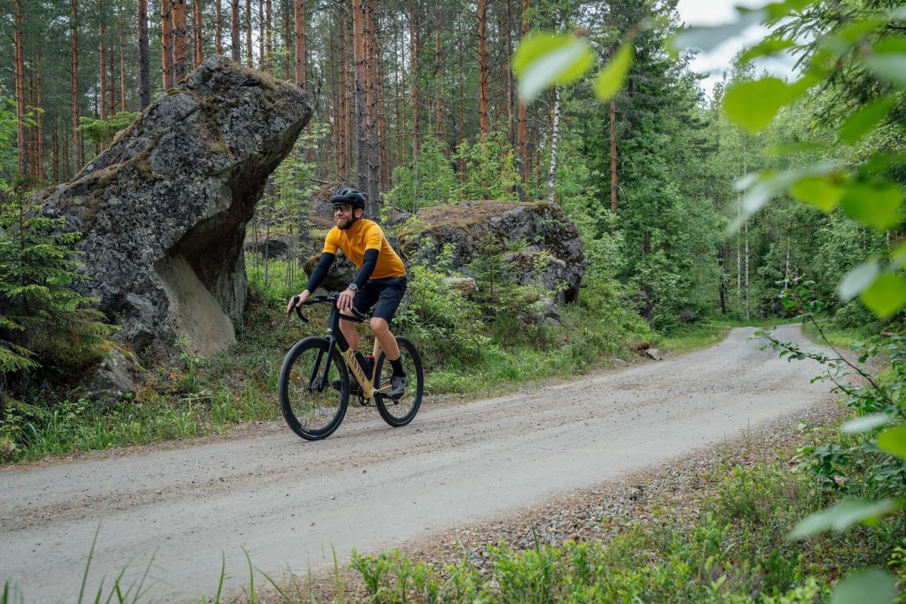 Pyöräilijä metsäisellä soratiellä.
