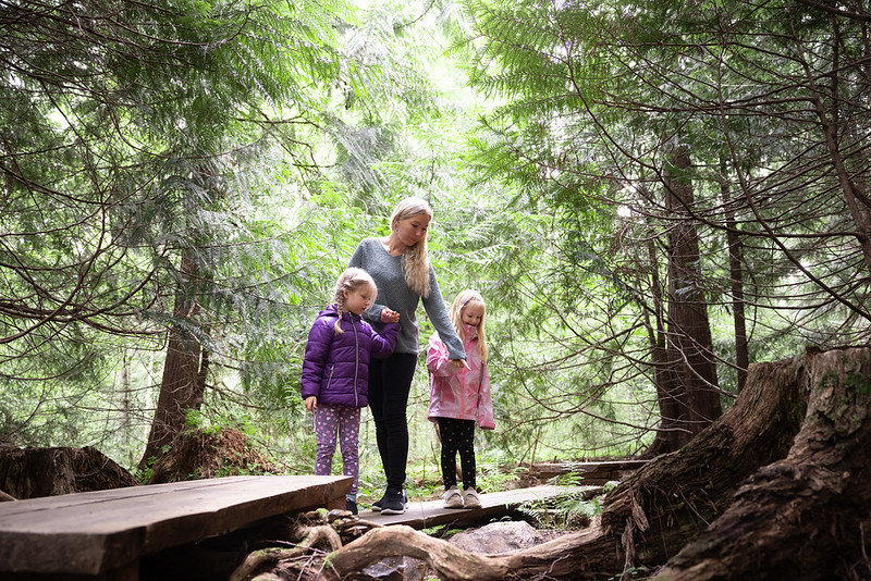 Äiti kahden lapsen kanssa metsässä.