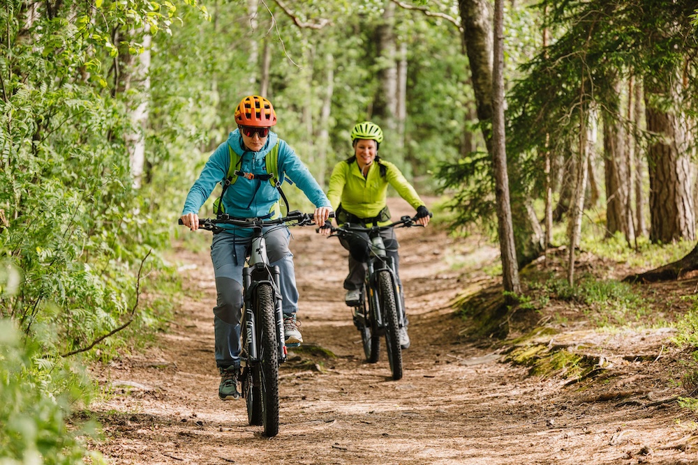 Kaksi ihmistä maastopyöräilevät metsässä.