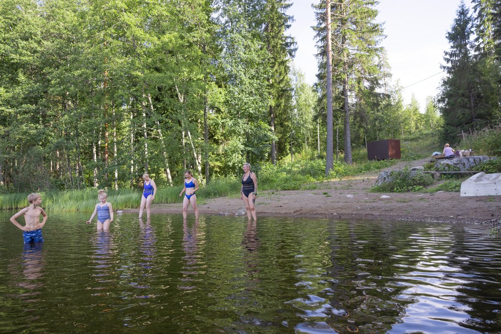 Ihmisiä uimarannalla menossa järveen uimaan.