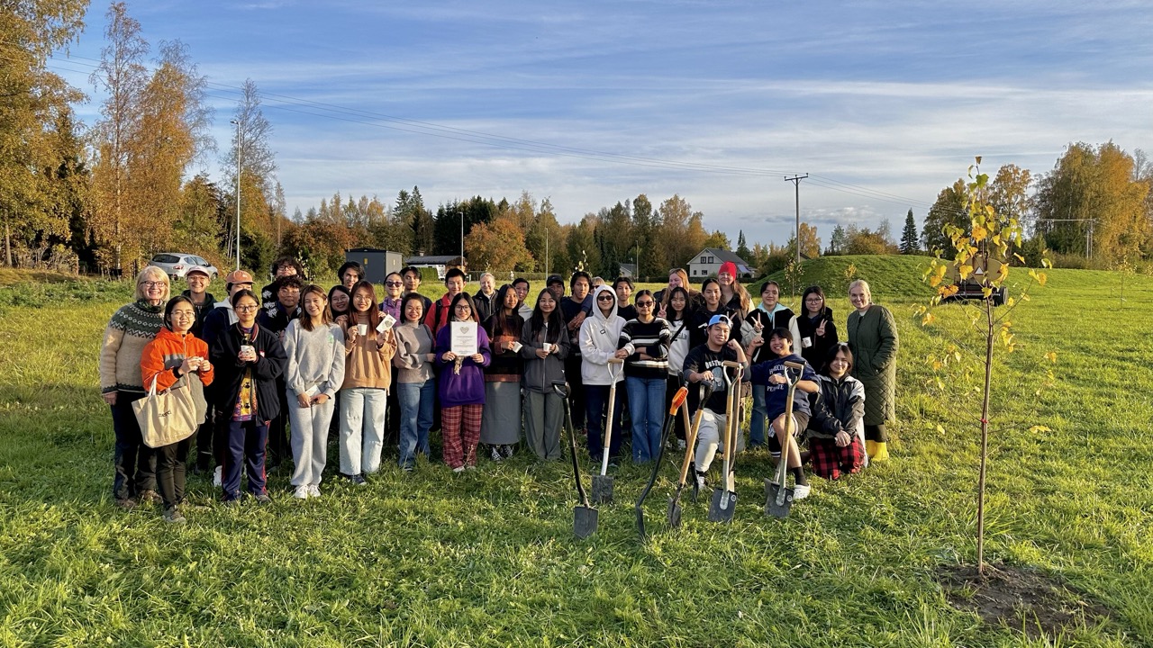 Nuoret poseeraavat kameralle nurmikolla aurinkoisena syyspäivänä.