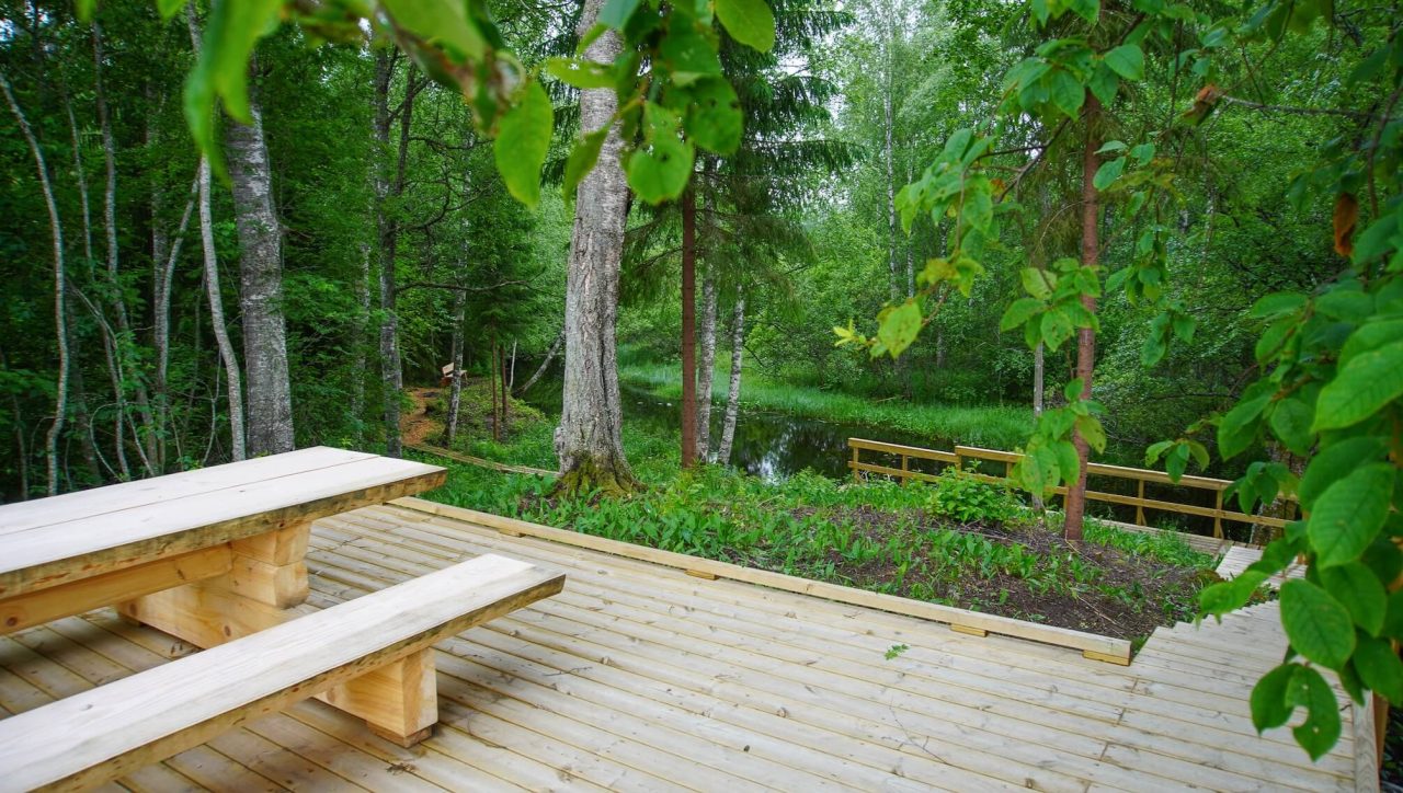 Pöytäpenkkiyhdistelmä terassilla rinteen yläpuolella. Alempana näkyy jokimaisema.