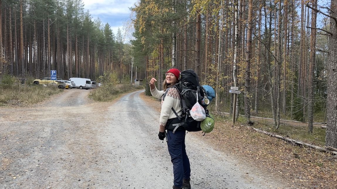 Nainen osoittaa rinkkaansa, jossa on roskapussi rinkan reunalla.